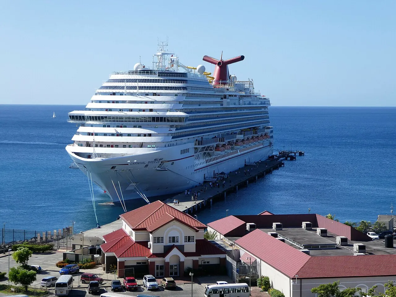 Colorful buildings of St. George's harbor with red tile roofs climbing the hillside above turquoise Caribbean waters