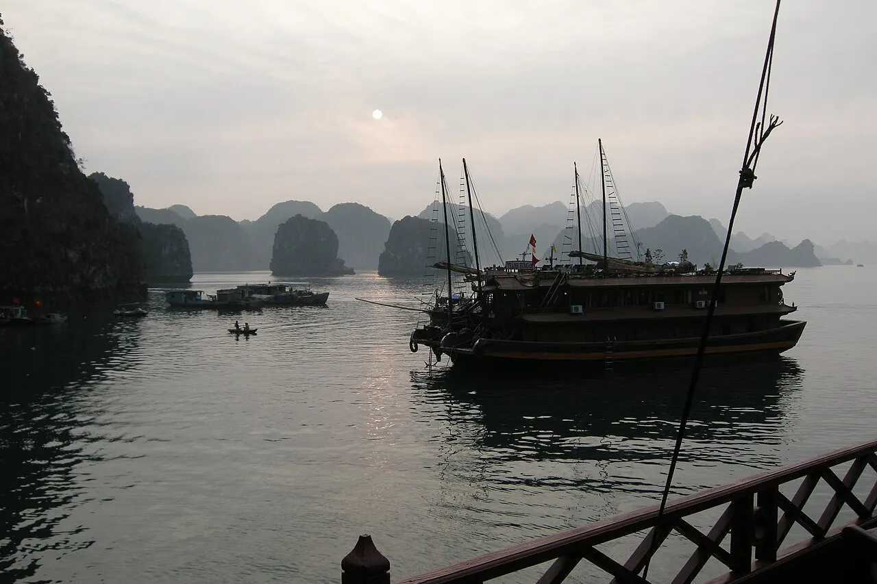 Traditional junk boats at dusk among Ha Long Bay karst formations