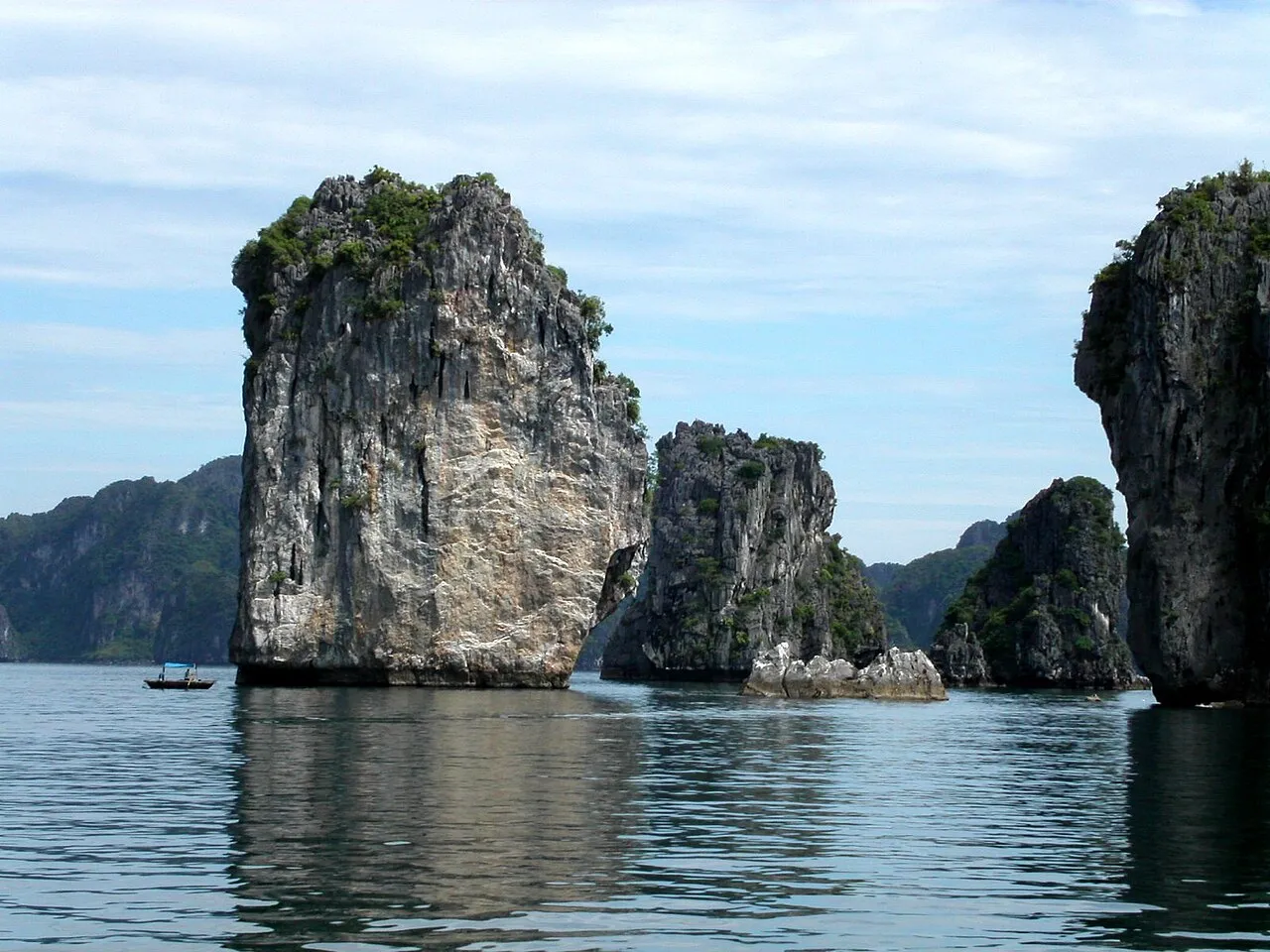 Dramatic karst pillars on a clear day in Ha Long Bay with fishing boat