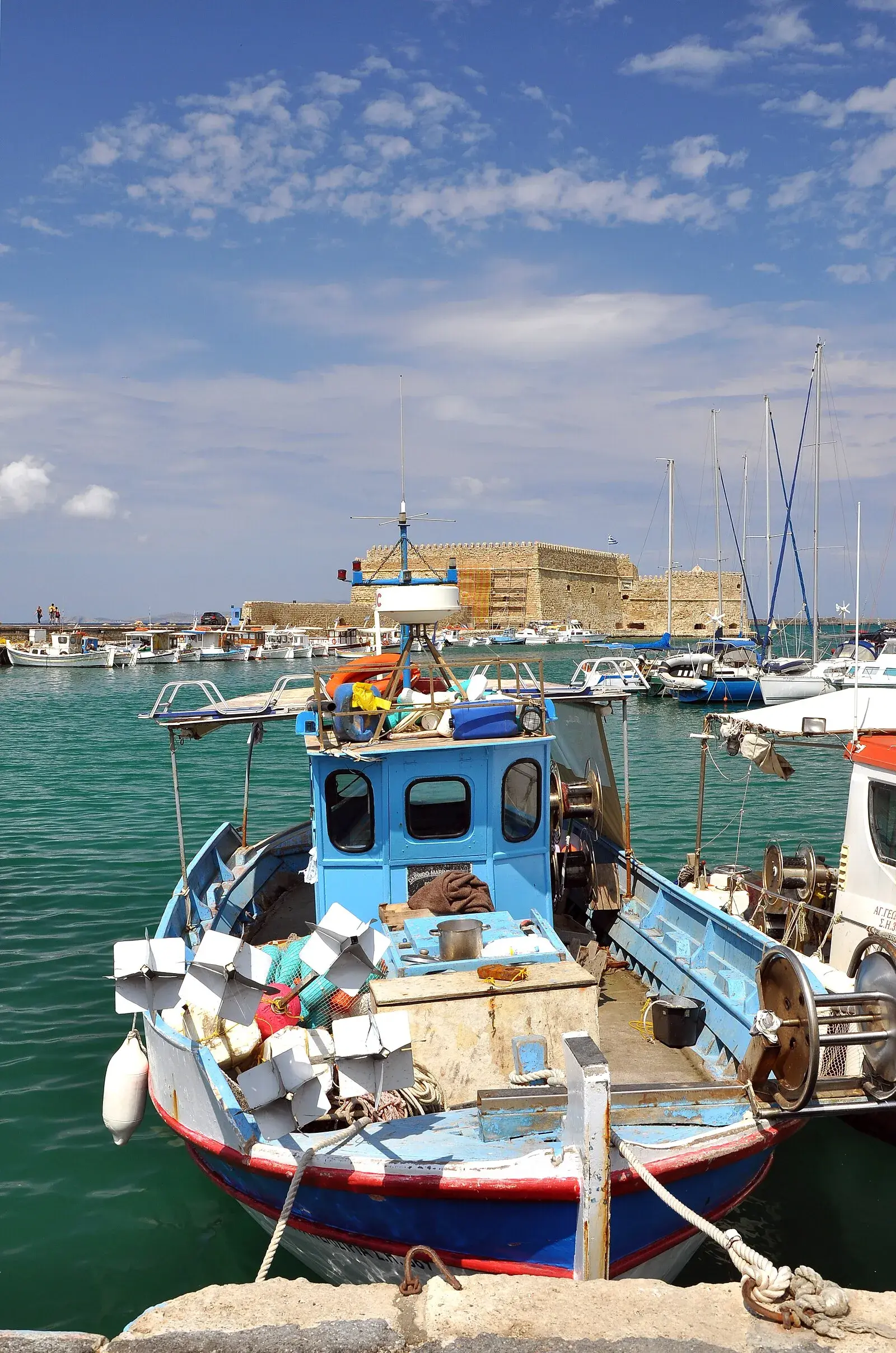 Blue fishing boat in Heraklion's Venetian harbor with Koules Fortress behind