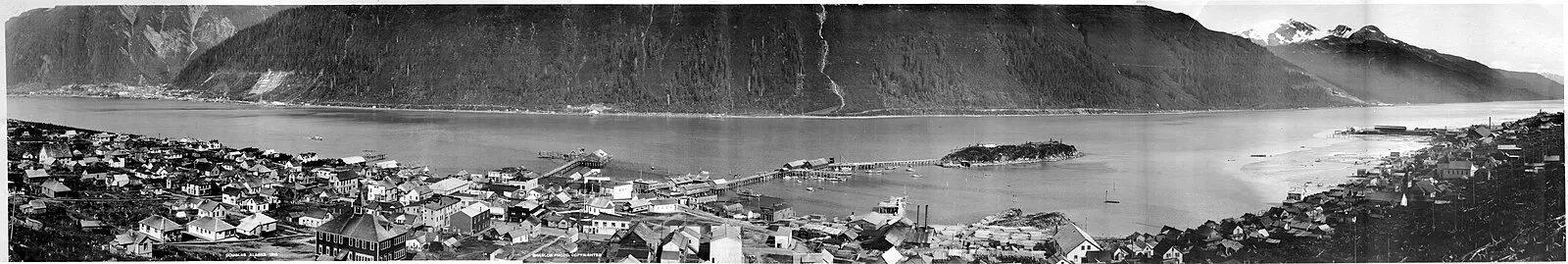 Historical black and white panoramic of early Juneau showing Gastineau Channel and Douglas Island