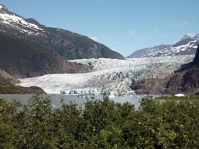 Mendenhall Glacier face calving into Mendenhall Lake with forested slopes