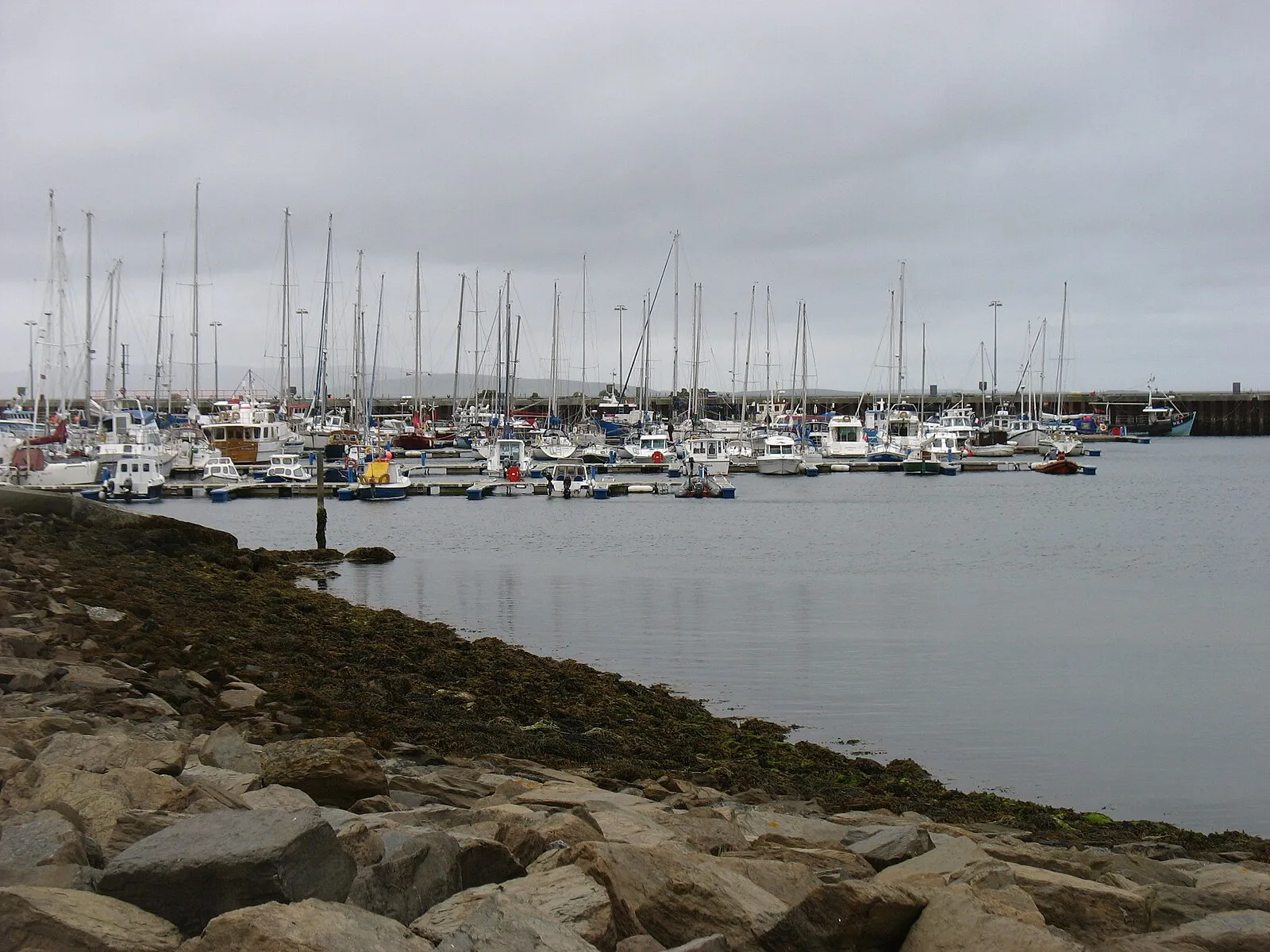 Kirkwall marina with sailing boats and fishing vessels from rocky shoreline