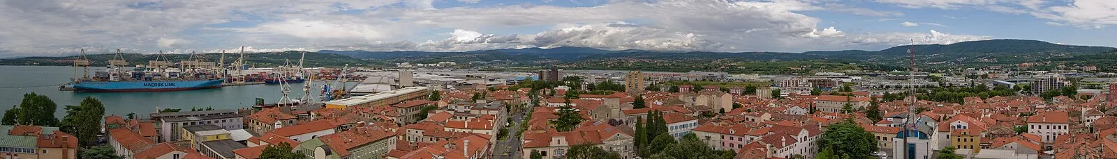 Panoramic view of Koper from cathedral bell tower showing red-roofed old town, Maersk container ship, port cranes, and Bay of Koper