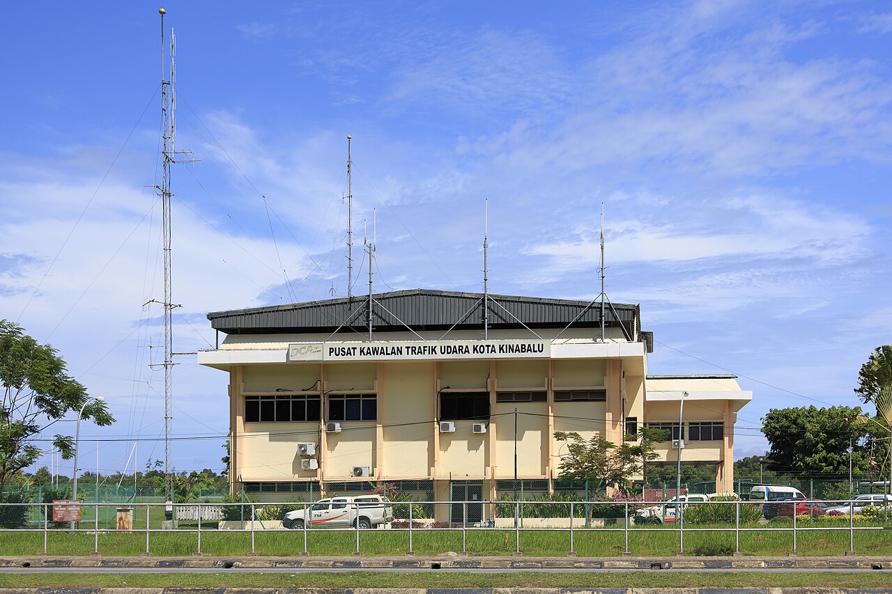 Downtown Kota Kinabalu street scene with colonial shophouses and tropical greenery lining the busy boulevard