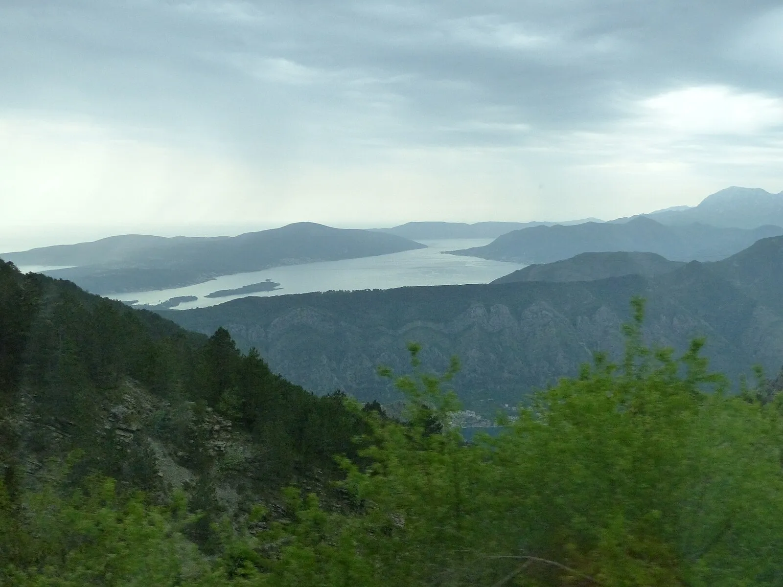 Our Lady of the Rocks island church in the Bay of Kotor with mountains and the village of Perast in the background