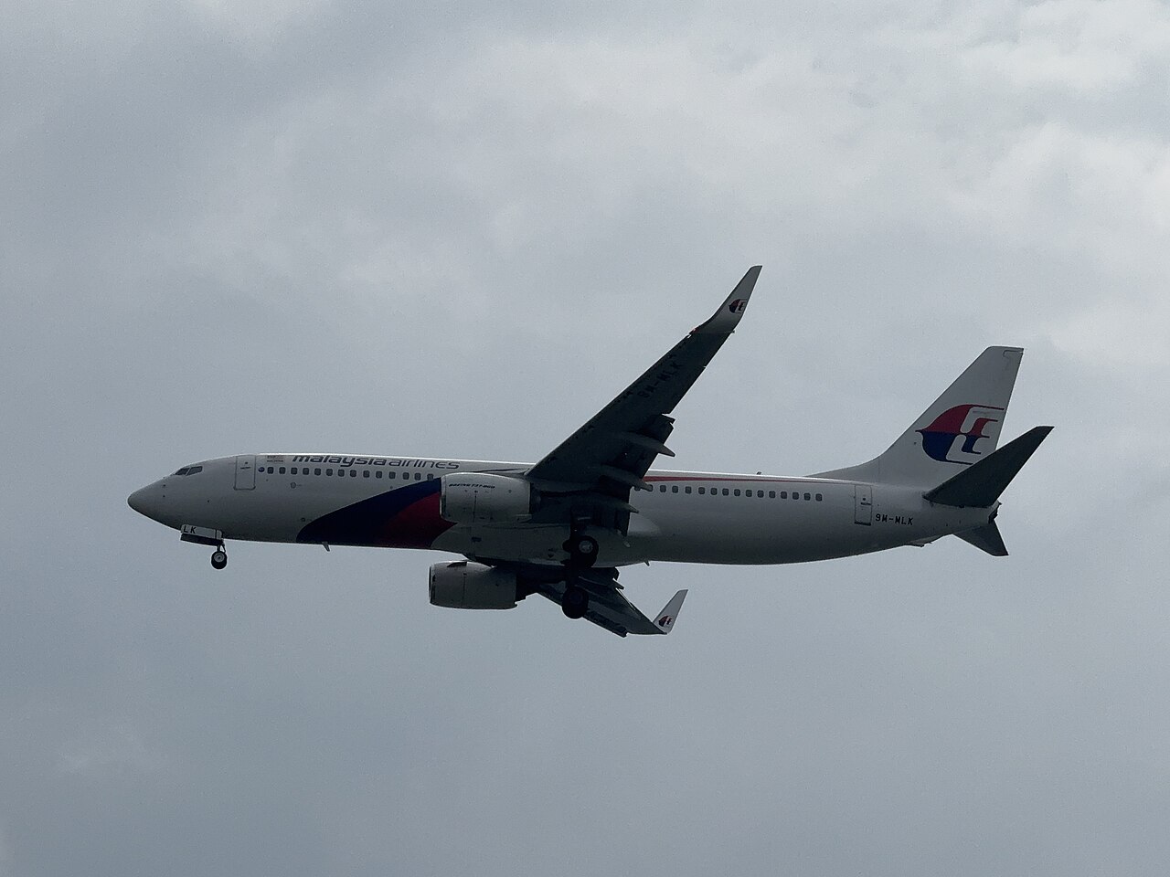 Interior of a limestone cave at Batu Caves with sunlight streaming through the collapsed ceiling onto shrines below