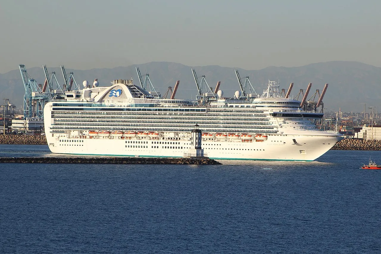 Cruise ship entering Port of Los Angeles channel with container cranes in background