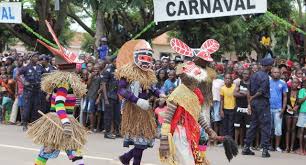 Angolan carnival dancers in traditional grass costumes performing under CARNAVAL banner in Luanda