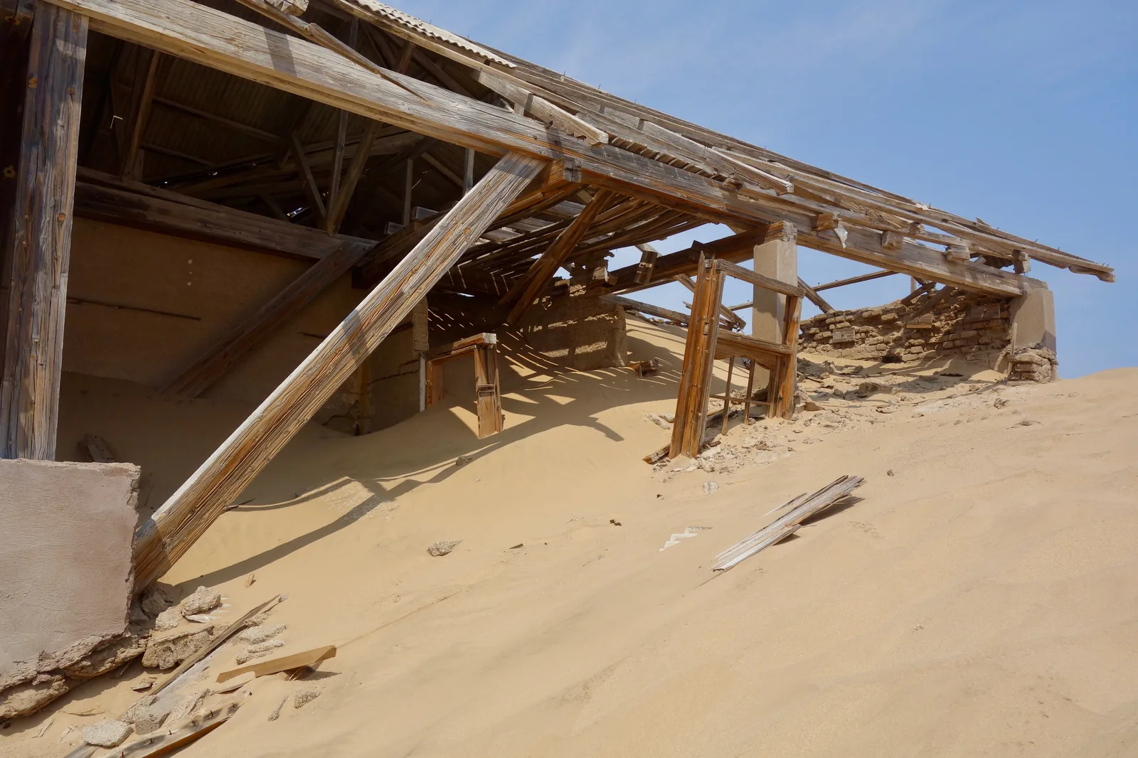 A collapsing building at Kolmanskop with sand drifted in under the roof timbers