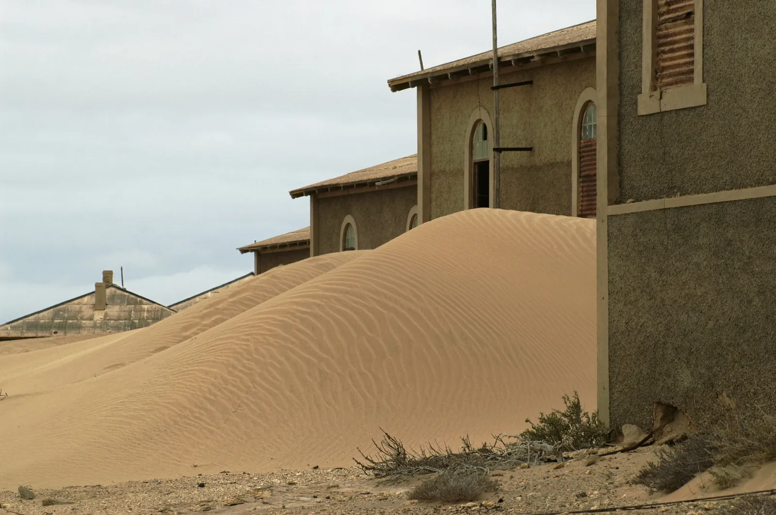 An abandoned building at Kolmanskop with sand drifted through the doorway and across the room