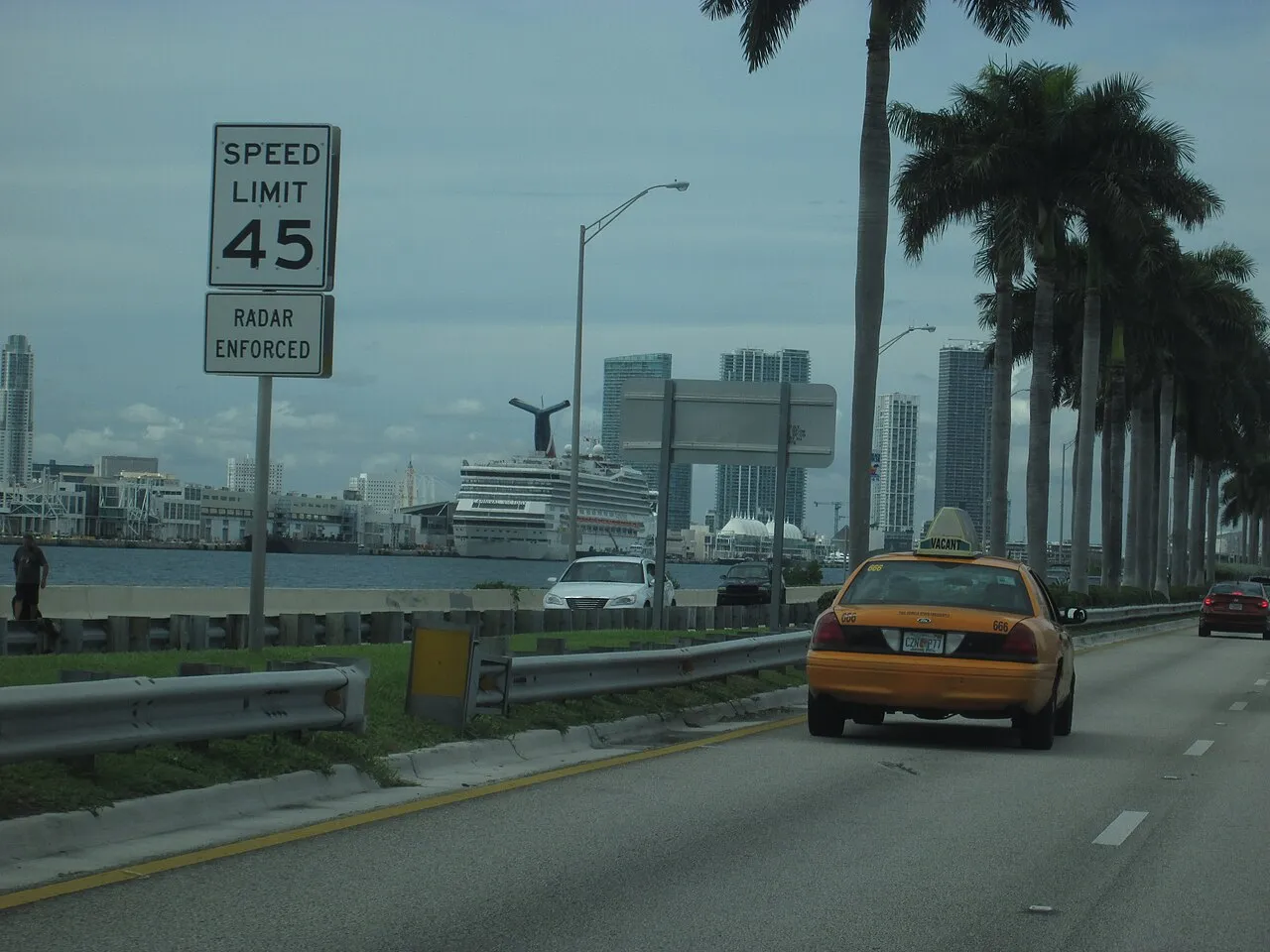 Approaching PortMiami via MacArthur Causeway with taxi, palm trees, and cruise ship