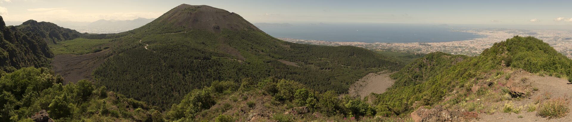 Naples waterfront with Mount Vesuvius rising dramatically behind the city and colorful buildings lining the bay