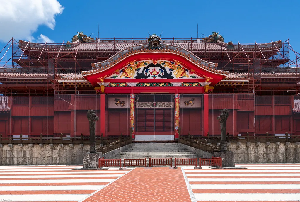 Shuri Castle gate and red-tiled rooftops overlooking Naha city under subtropical skies in Okinawa, Japan
