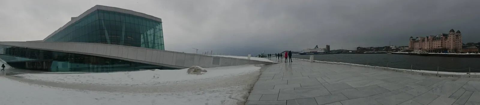 Oslo Opera House in winter with snow-covered roof and harbor panoramic