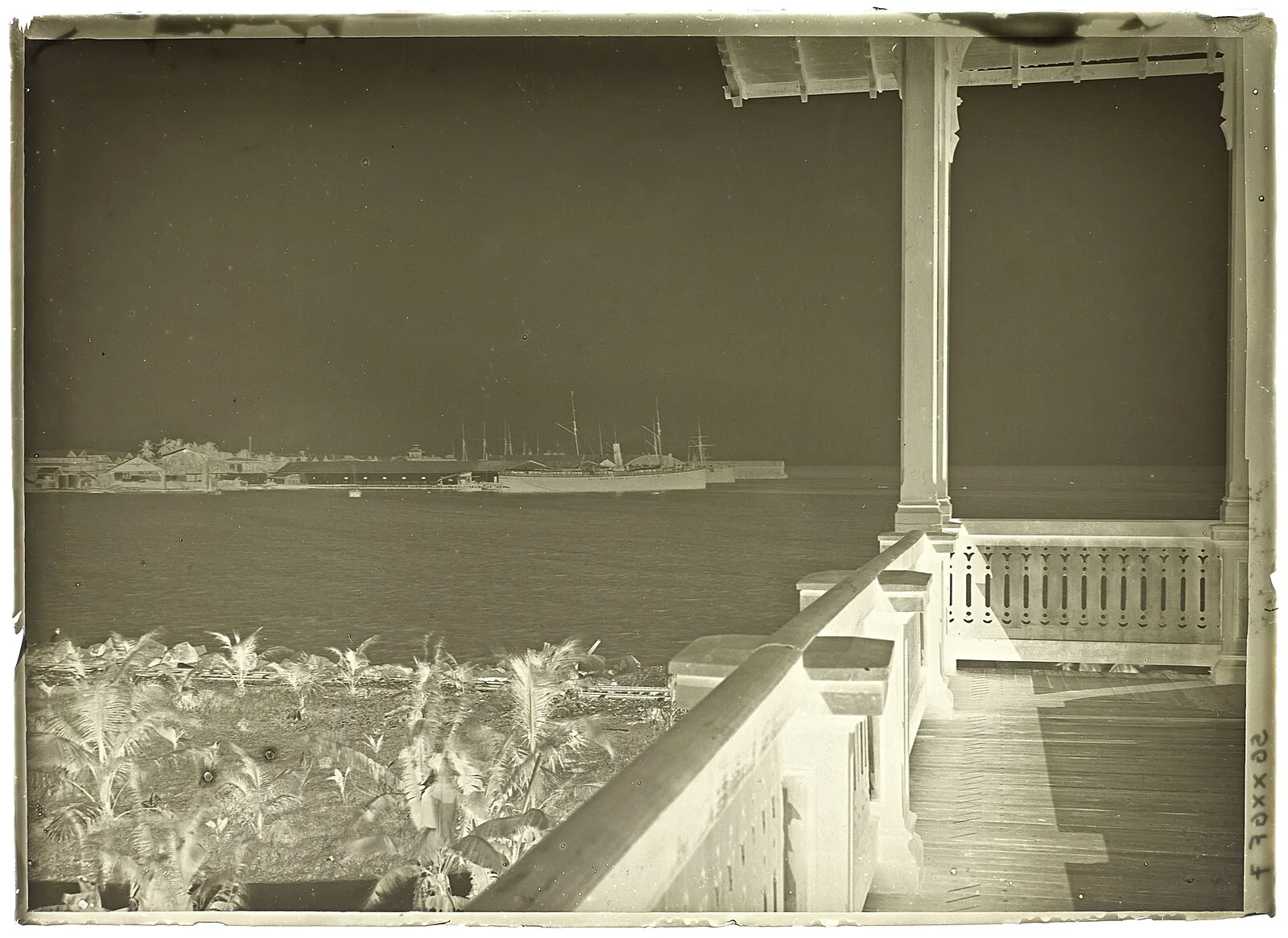 Historical sepia photograph from colonial veranda overlooking Panama Canal Zone harbor with sailing ships