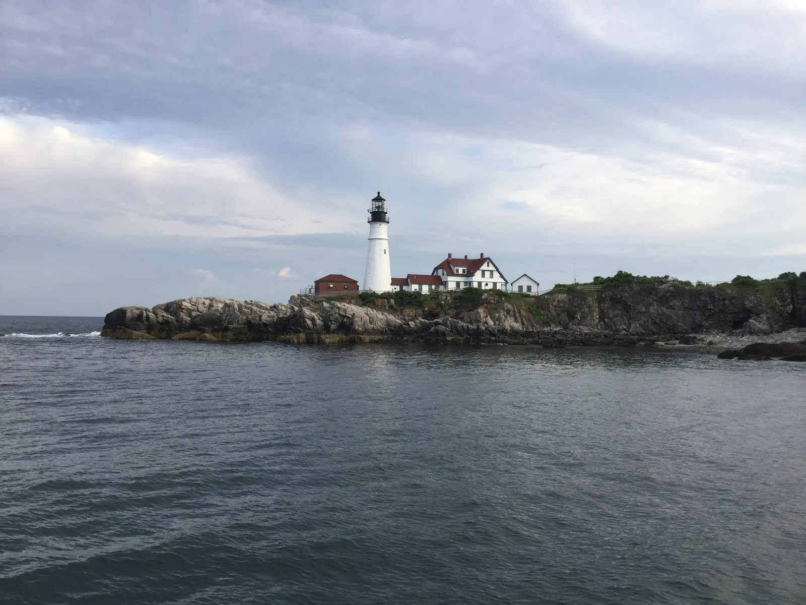 Spring Point Ledge lighthouse at the end of a granite breakwater stretching into Portland harbor with waves crashing