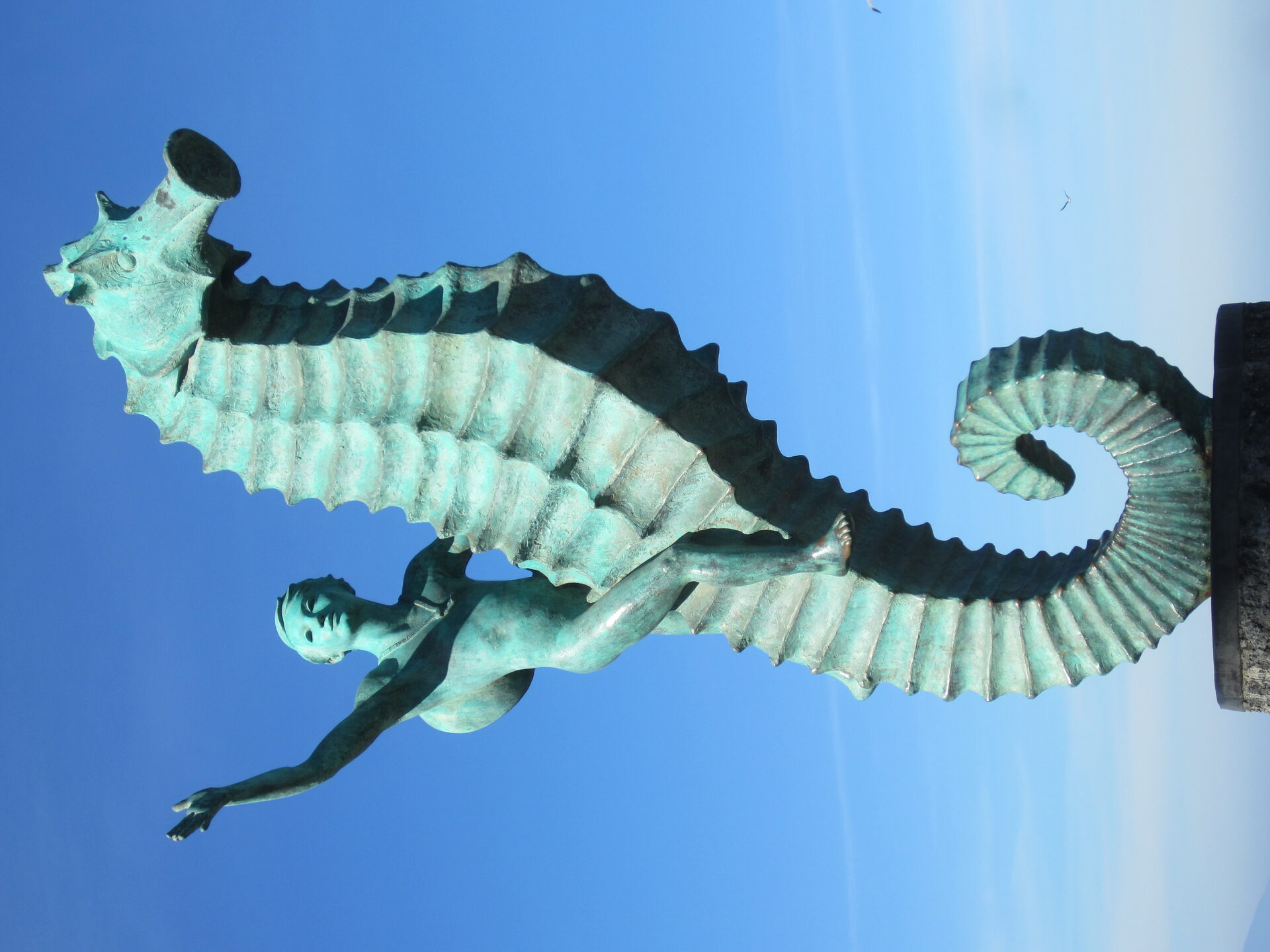 Puerto Vallarta's cobblestone Malecon boardwalk with bronze sculptures and Sierra Madre mountains rising behind red-roofed buildings