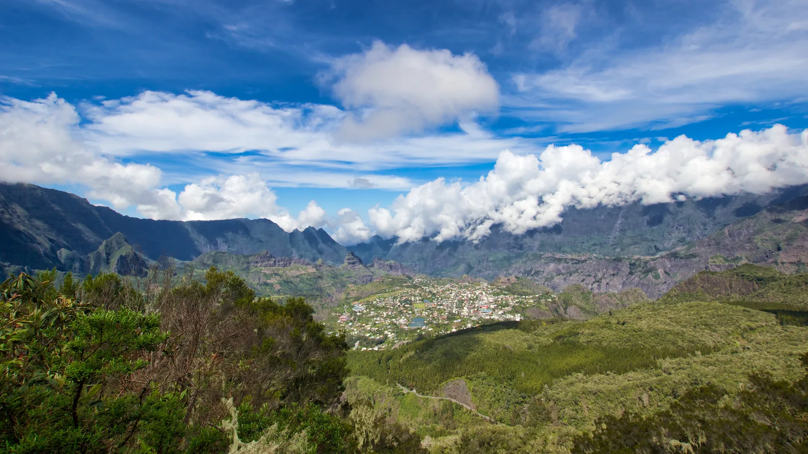 The town of Cilaos surrounded by the towering walls of its cirque, with cloud pouring over the rim