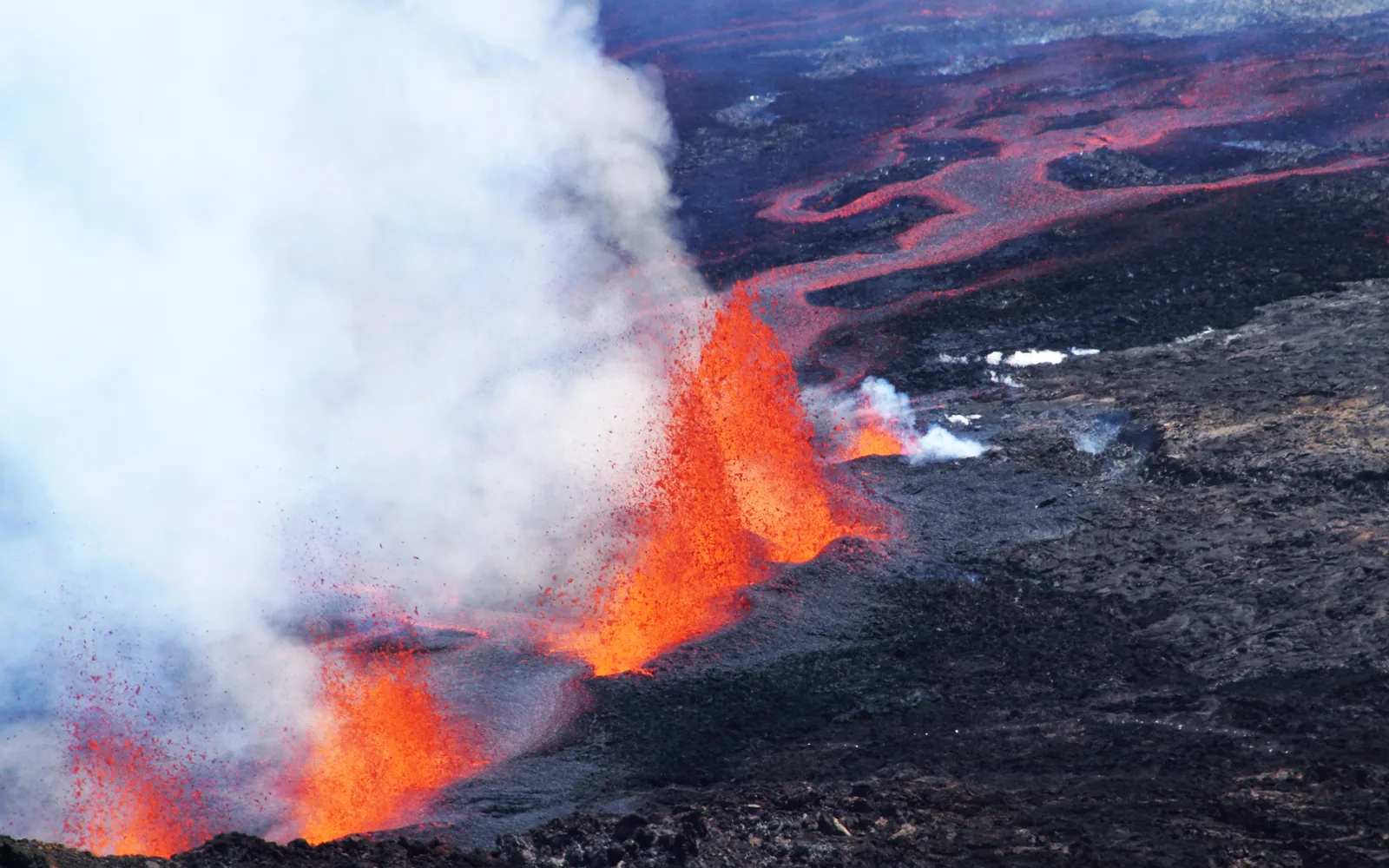Lava fountains rising twenty to thirty metres above a fissure on Piton de la Fournaise with glowing flows running downslope