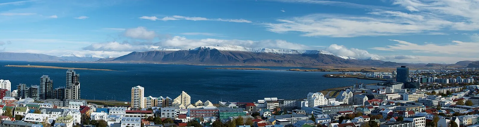 Panoramic from Hallgrímskirkja showing colourful rooftops, bay, and Mount Esja