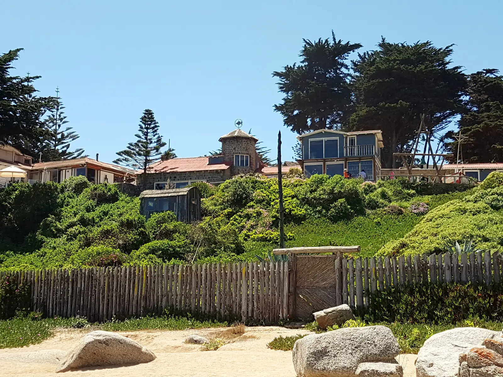 Pablo Neruda's stone and timber house at Isla Negra seen from the beach, standing above the rocks with the Pacific in the foreground
