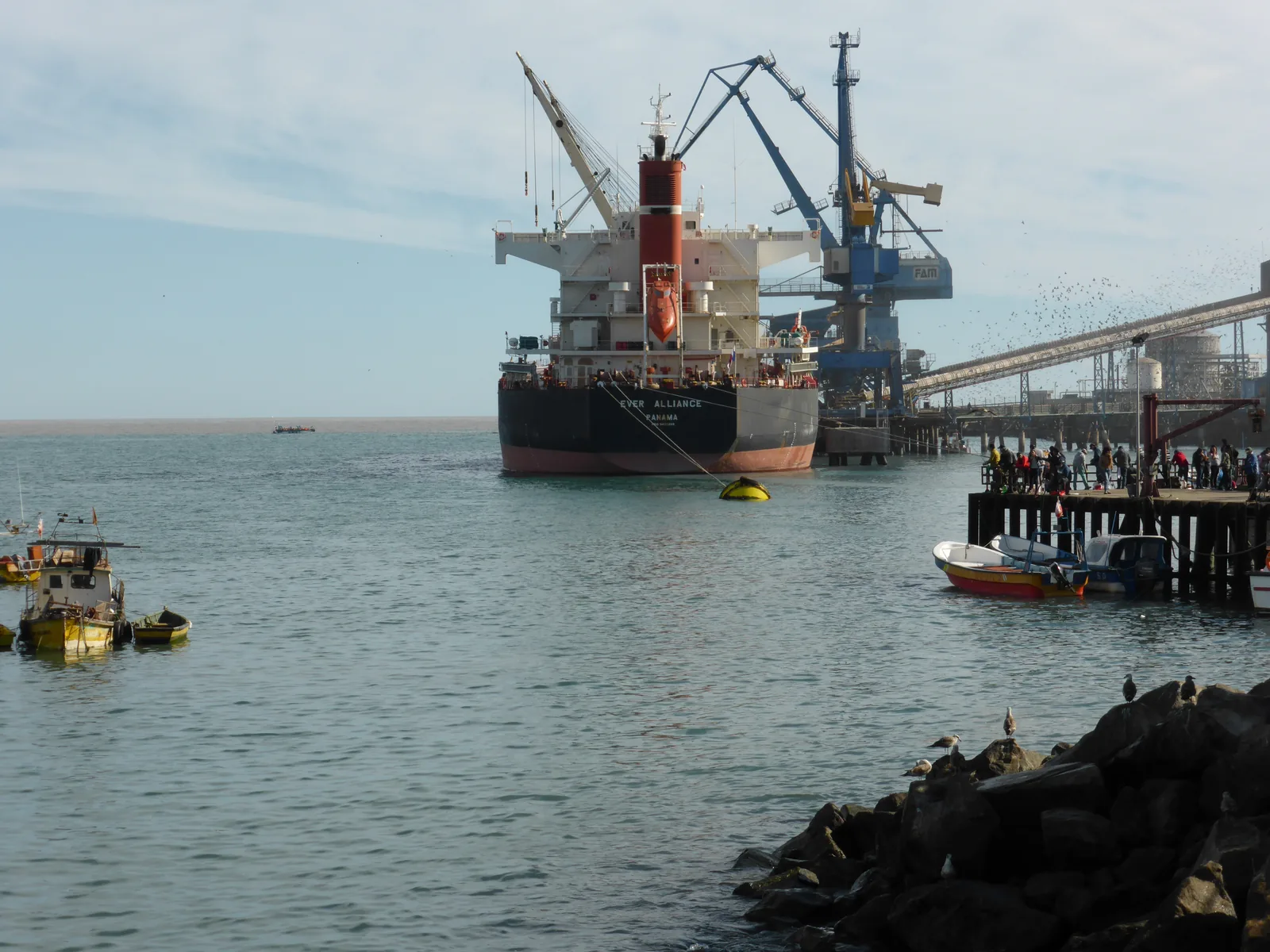 A ship alongside a quay at the Port of San Antonio with cargo handling equipment behind