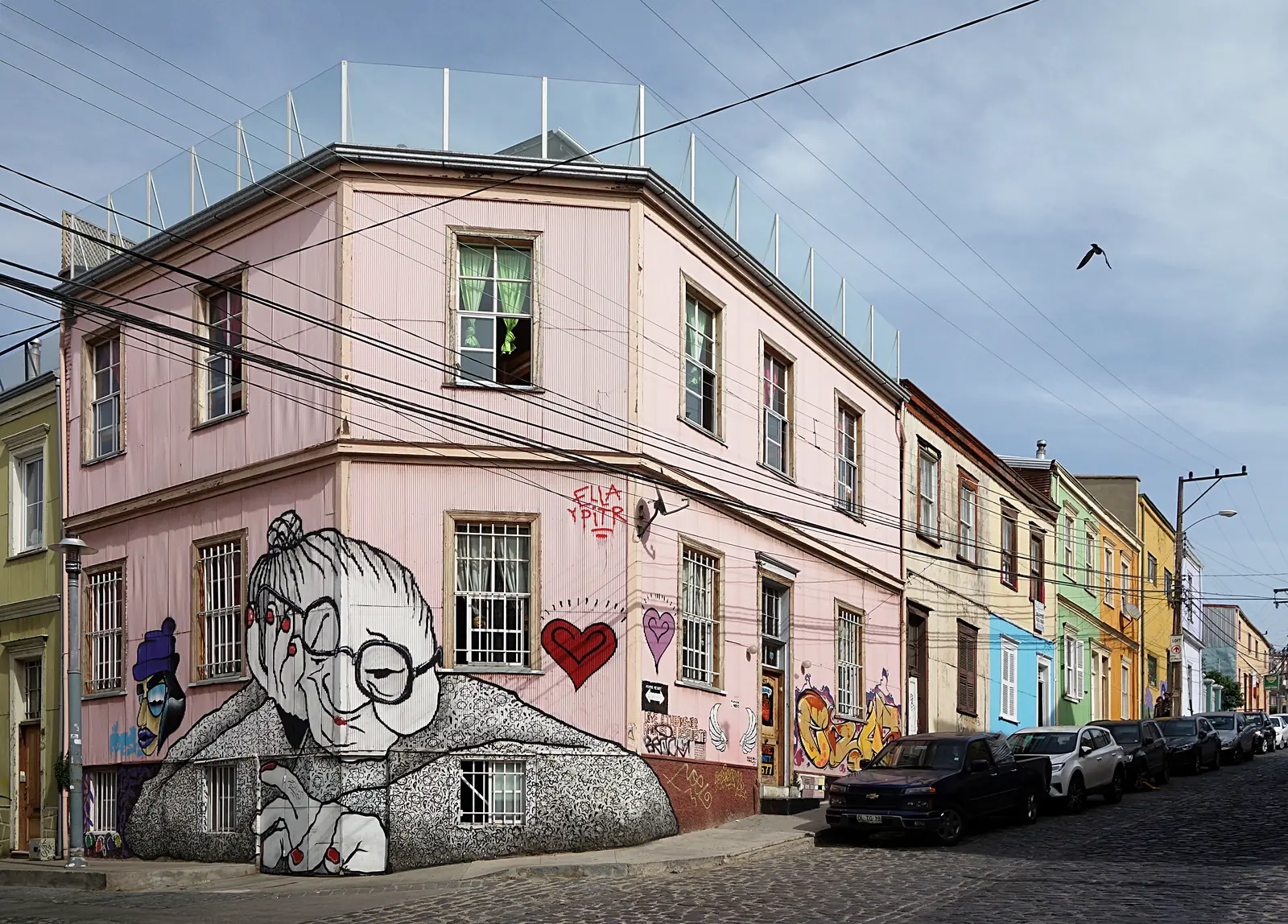 A large colourful mural painted across the wall of a building on a steep street in Valparaíso