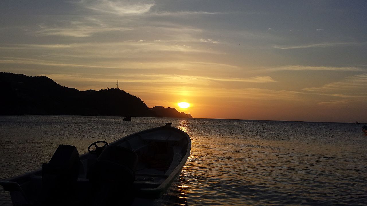 Sunset over Santa Marta bay with a fishing boat silhouetted against the sky
