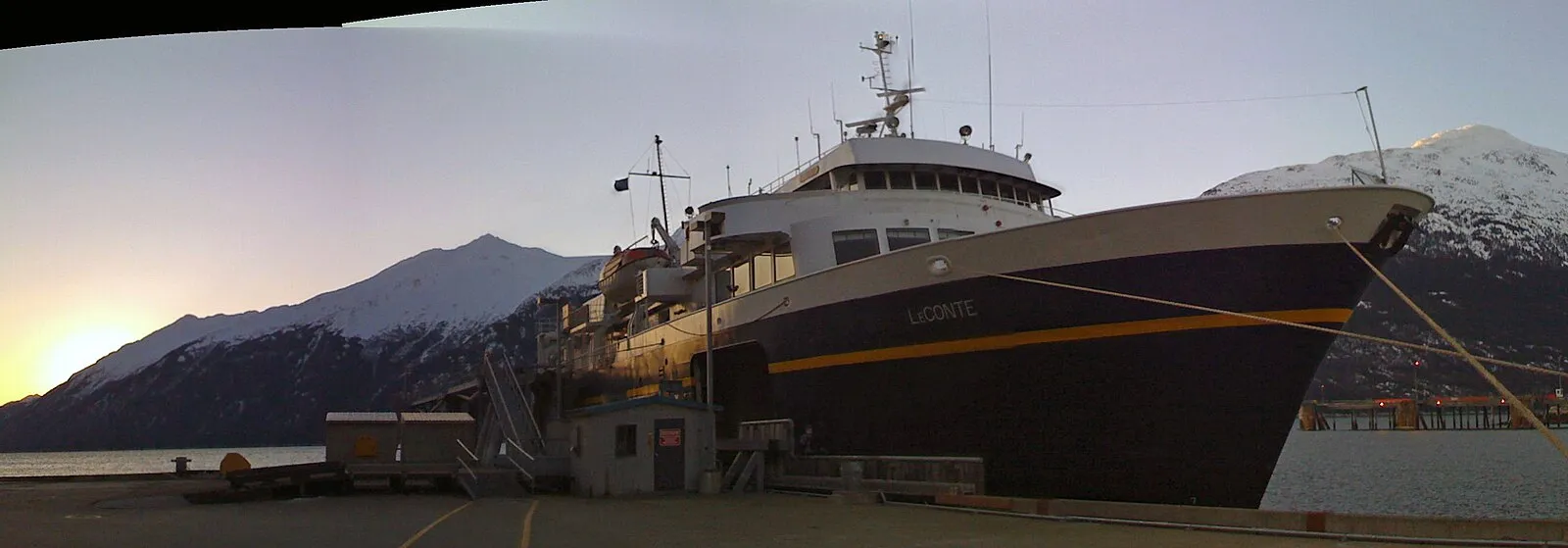 Alaska Marine Highway ferry LeConte docked at Skagway with snow-capped mountains at sunset