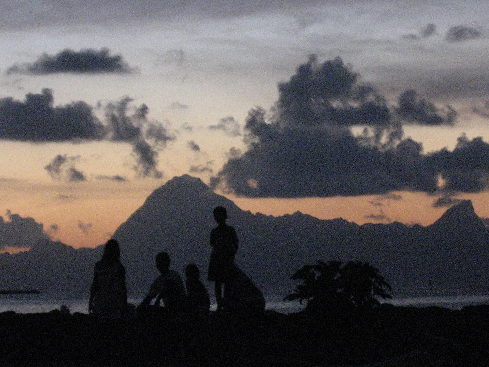 Silhouettes at sunset with volcanic mountain peaks on a South Pacific island