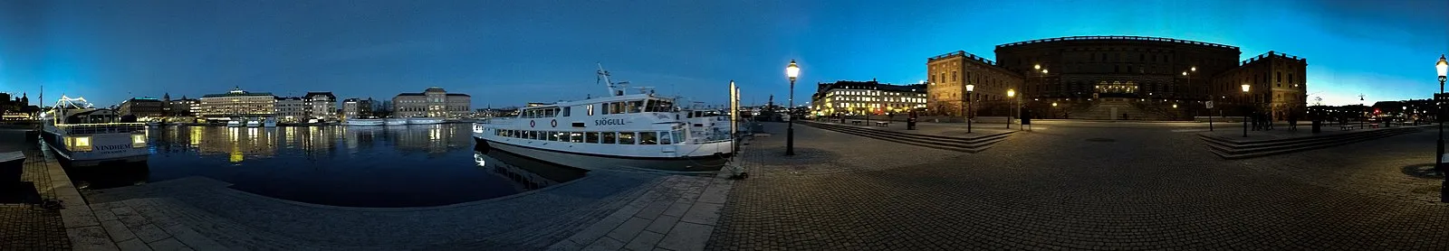Stockholm waterfront at blue hour with Sjögull tour boat, Royal Palace, and city lights reflected on water