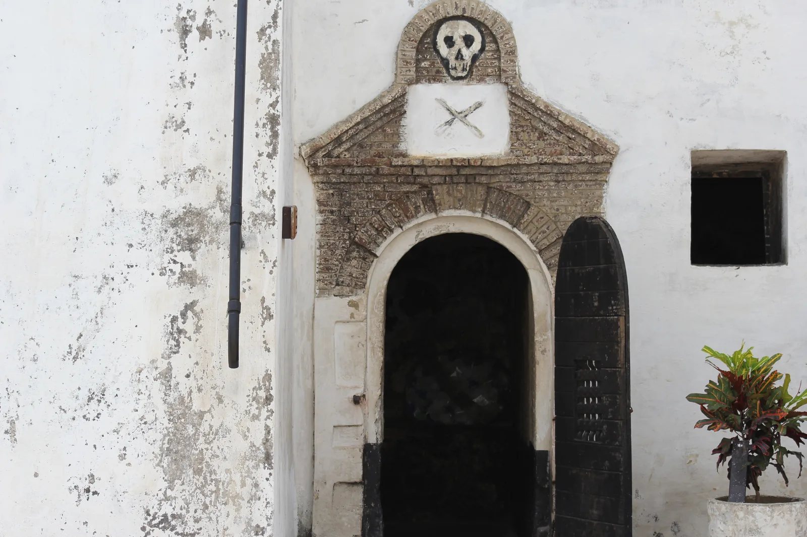 The condemned cell at Elmina Castle, a small dark chamber with a barred door