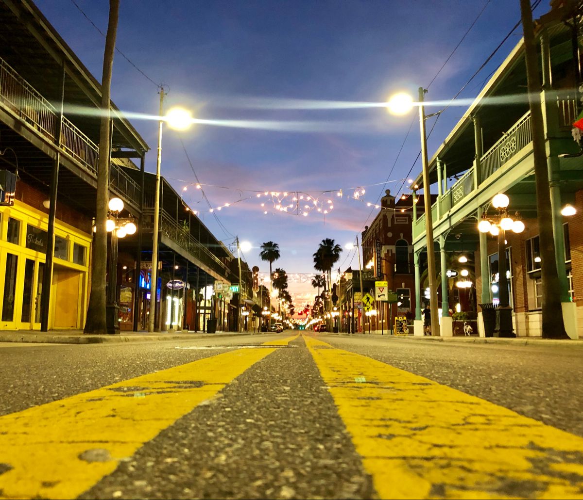 7th Avenue in Ybor City at dusk with string lights, palm trees, and wrought-iron balconies