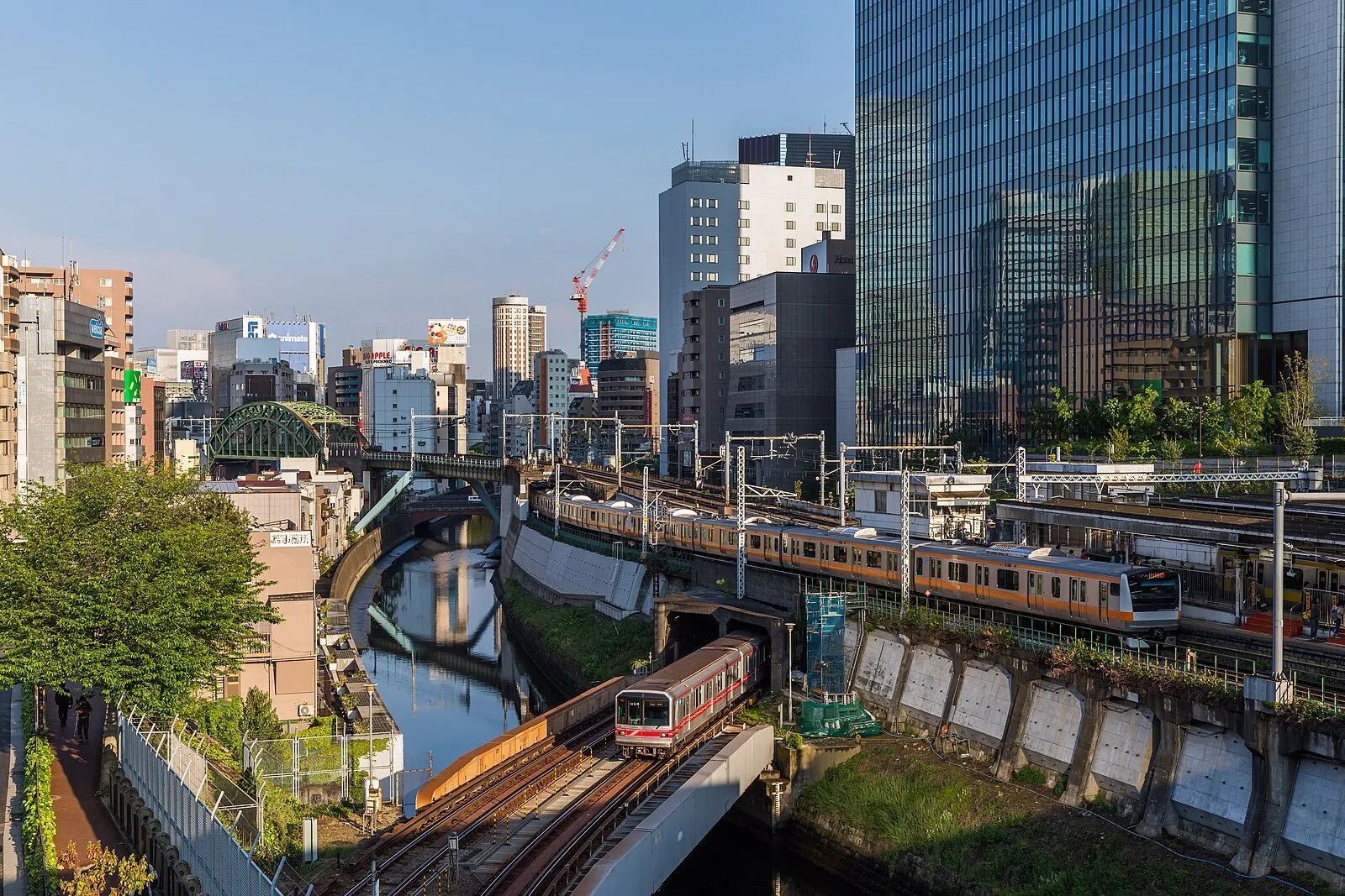 Ochanomizu rail junction showing multiple JR and Metro lines converging over Kanda River with Tokyo office buildings
