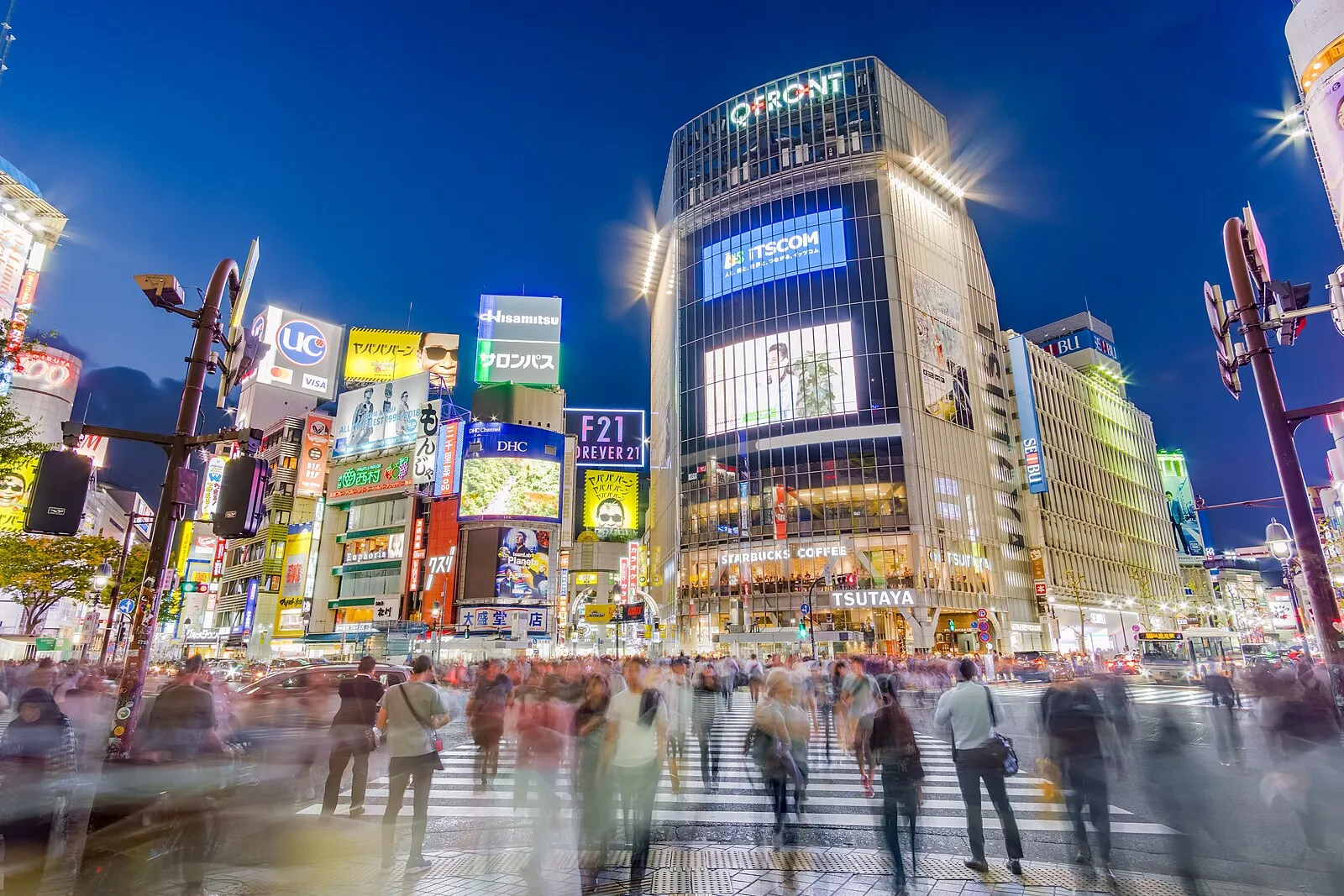Shibuya Crossing at night with QFRONT building, neon signs, and blurred pedestrians in long exposure