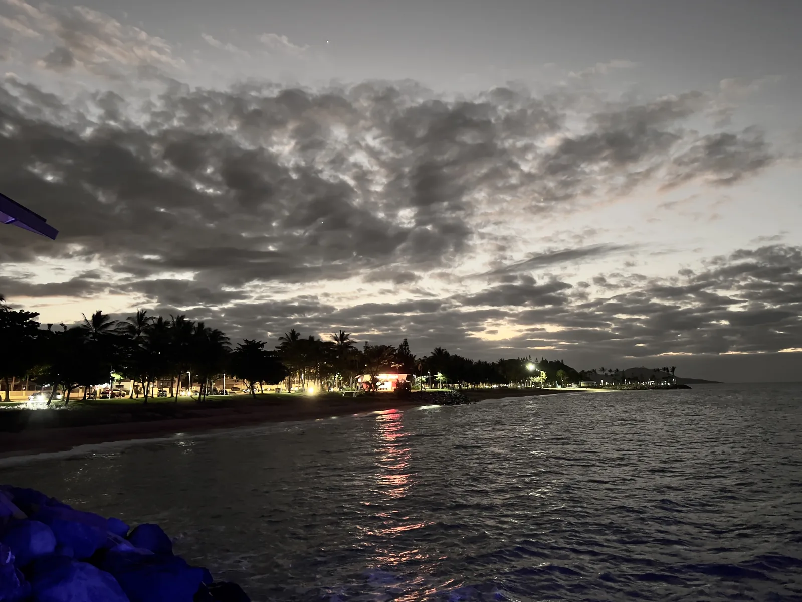The Strand foreshore at dusk seen from the Strand Pier, with palms, beach lighting and a rock revetment