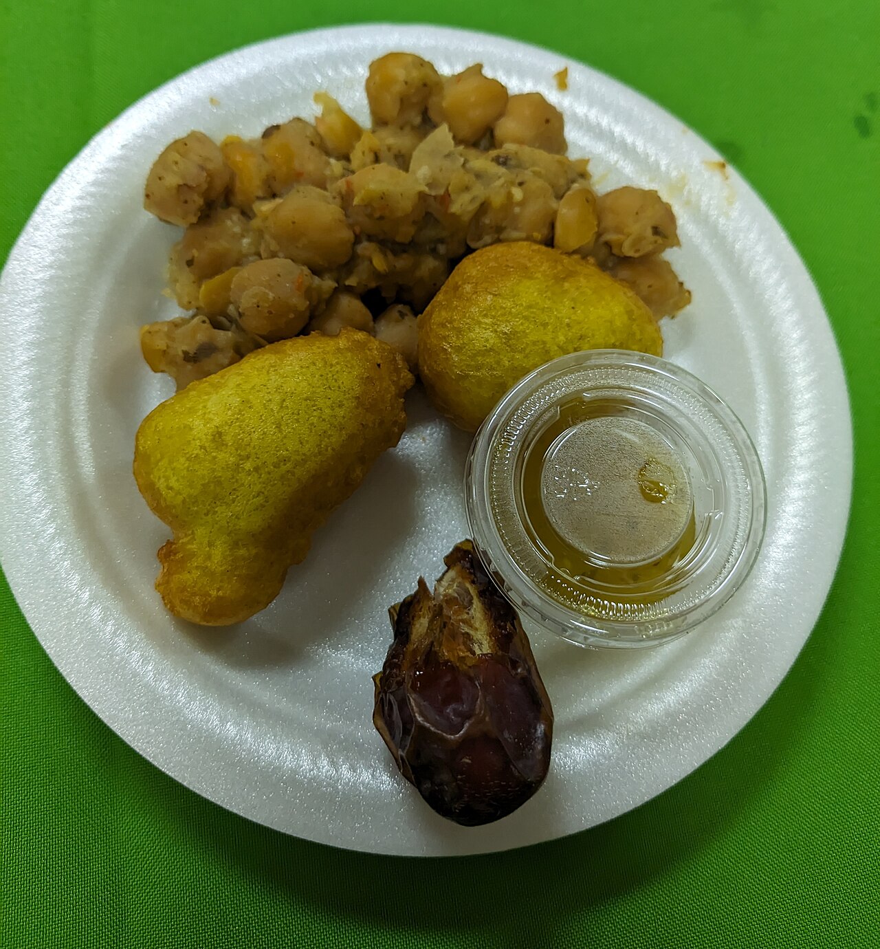Trinidadian iftar plate with pholourie (fried split-pea balls), channa (curried chickpeas), date, and honey