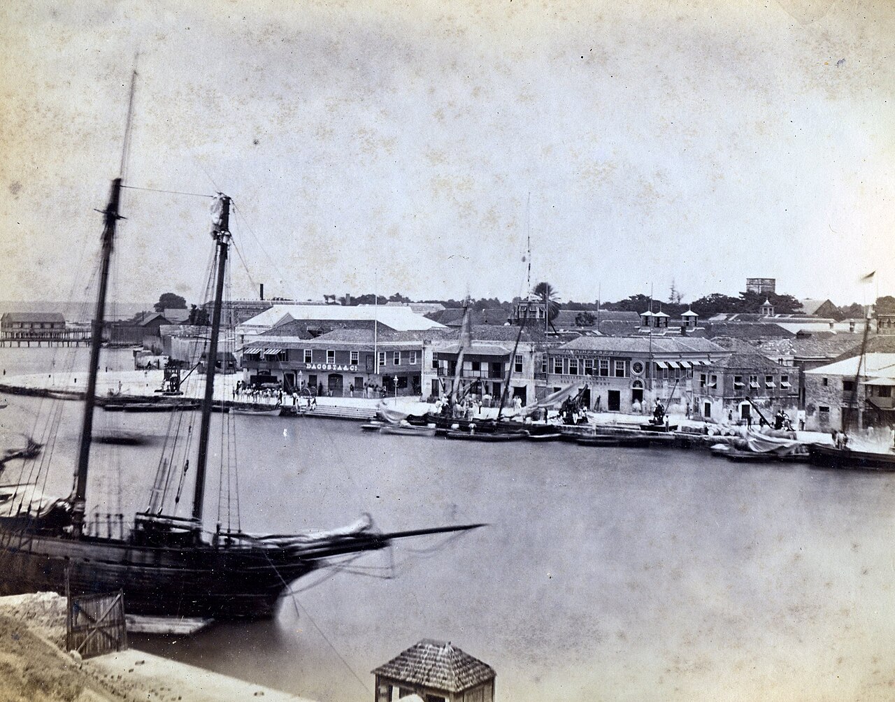 Historic photograph of Port of Spain harbor with sailing vessels and colonial waterfront buildings