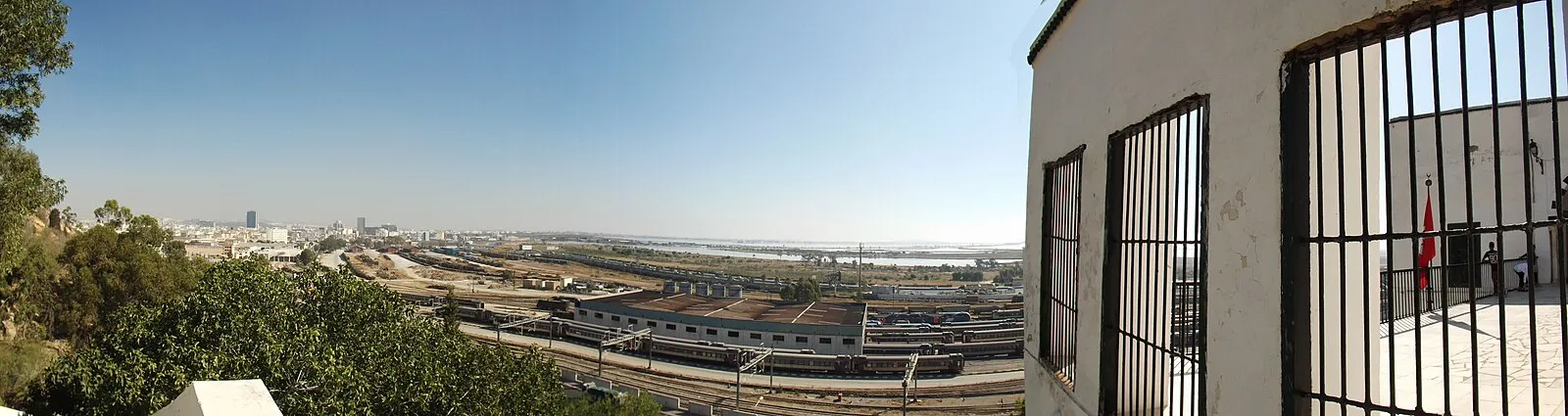 Panoramic view of Tunis port and railway yards from historic building terrace with Tunisian flag