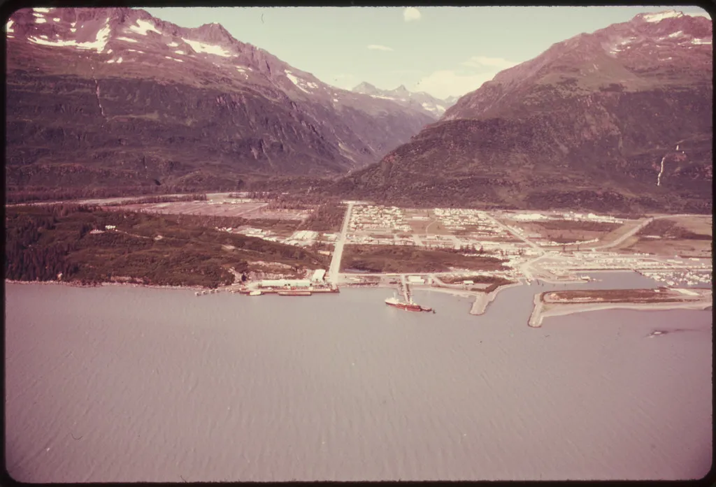Aerial view north across Port Valdez to the city of Valdez surrounded by Chugach Mountains, circa 1974