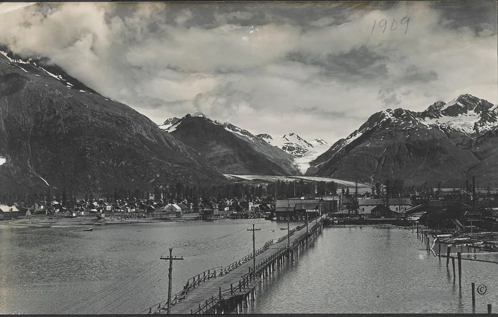 Panoramic view of Valdez nestled at the head of a fjord with snow-capped Chugach Mountains