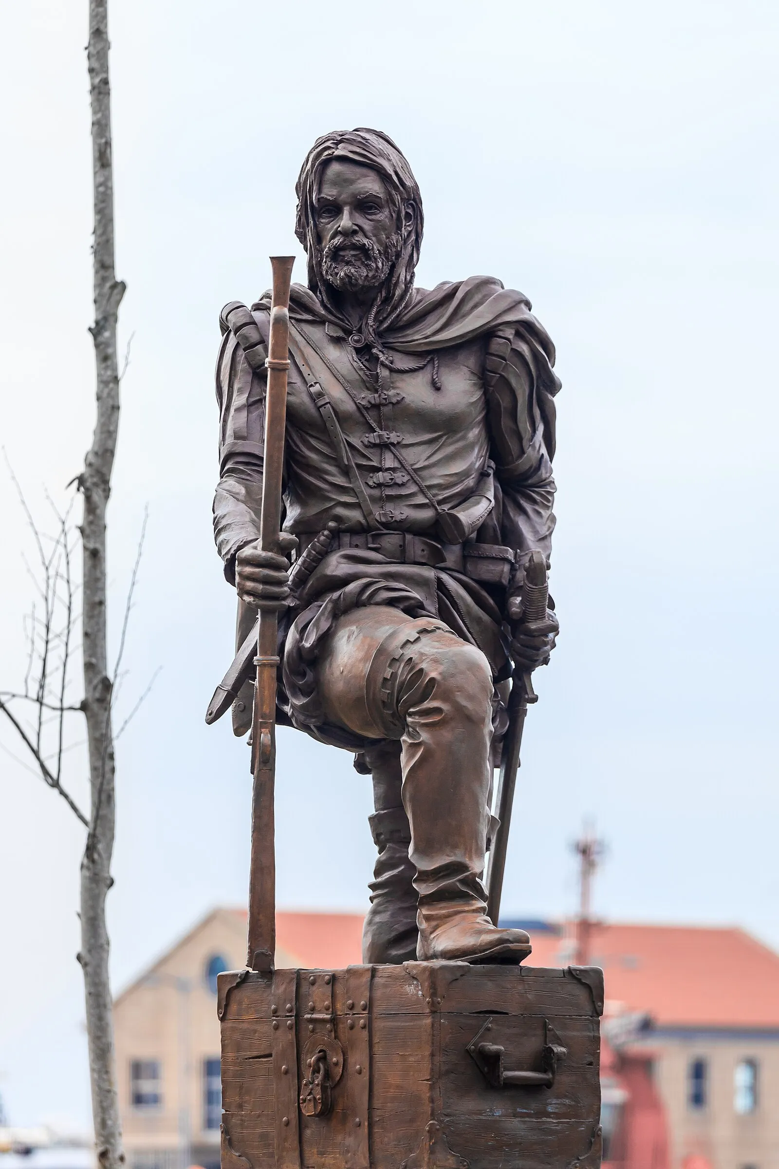 Bronze explorer statue seated on treasure chest with musket in Vigo, Spain