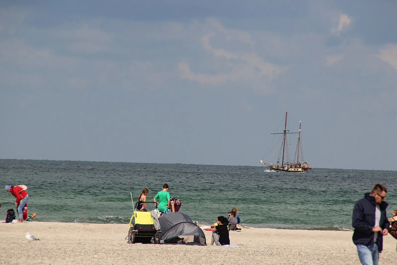 Warnemünde beach with traditional tall ship sailing past in the Baltic Sea