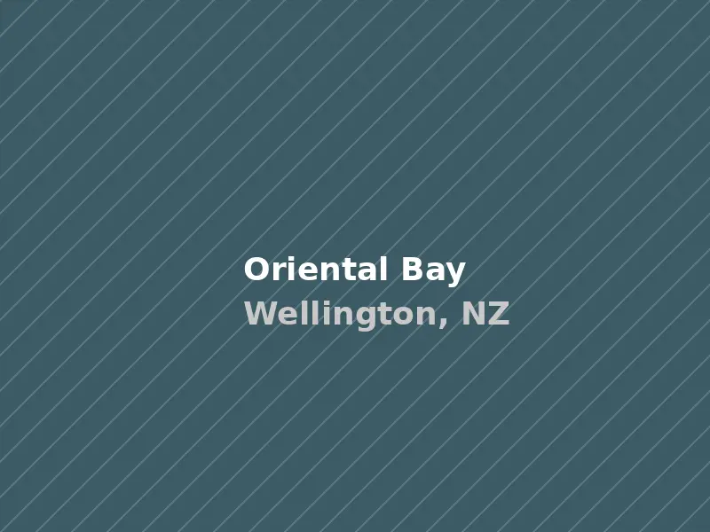 Sandy beach and calm water at Oriental Bay with city skyline and hillside houses behind