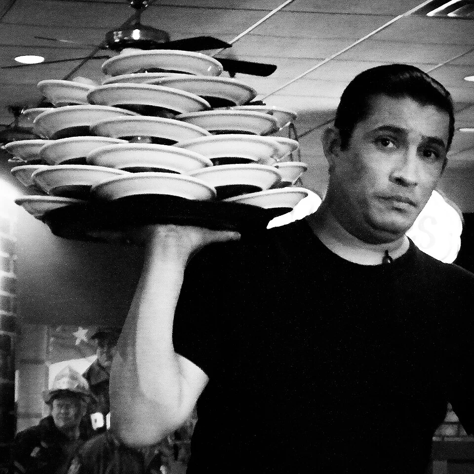 Waiter serving guests in a bustling restaurant—an emblem of U.S. service and tipping culture.